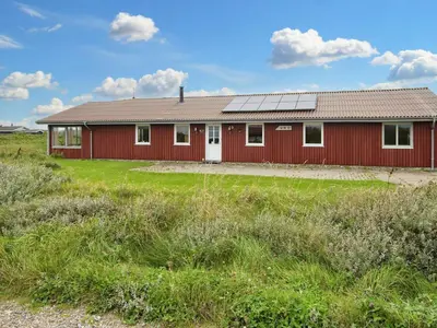 a red building with a solar roof on a field at 10 person holiday home in Harboøre-By Traum in Harboør