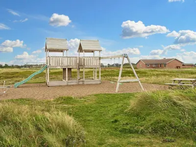 a playground with two swings in a field at 10 person holiday home in Harboøre-By Traum in Harboør