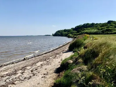 a sandy beach next to a body of water at 5 person holiday home in Roslev-By Traum in Roslev