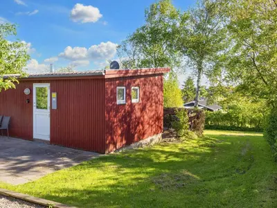 a red shed with a white door in a yard at 5 person holiday home in Roslev-By Traum in Roslev