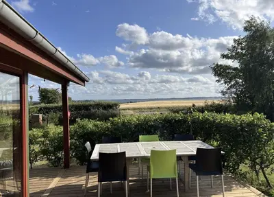 a dining table and chairs on a deck with a view at Holiday Home By Limfjord With Historic Charm in Farsø