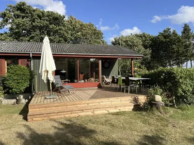 a house with a deck with a table and an umbrella at Holiday Home By Limfjord With Historic Charm in Farsø