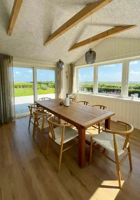 a dining room with a wooden table and chairs at Summer House With Wilderness Bath And Water Views in Vinderup