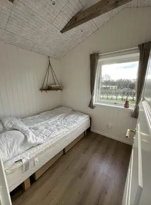 a small bedroom with a bed and a window at Summer House With Wilderness Bath And Water Views in Vinderup