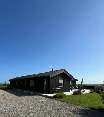 a black house with a gravel driveway at Summer House With Wilderness Bath And Water Views in Vinderup