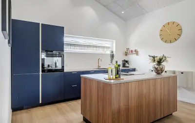 a kitchen with blue cabinets and a clock on the wall at Gorgeous Home In Saltum With Wifi in Saltum