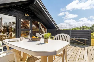 a patio with a white table and chairs on a deck at Lovely Holiday Home With Wood-Burning Stove, Close To The North Sea In Klitmøller in Thisted