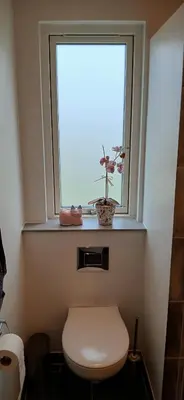 a bathroom with a toilet and a window with a flower at Blokhus - tæt på by og strand in Blokhus
