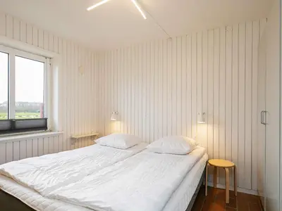 a white bedroom with a large bed and a window at 4-person cabin in Lemvig holiday park in Lemvig