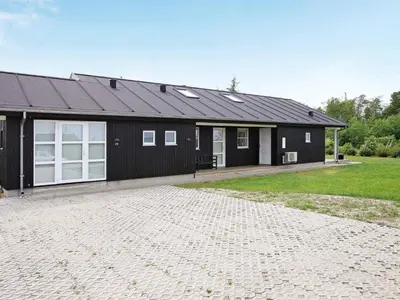 a black house with a driveway in front of it at 8 person holiday home in Brovst-By Traum in Brovst