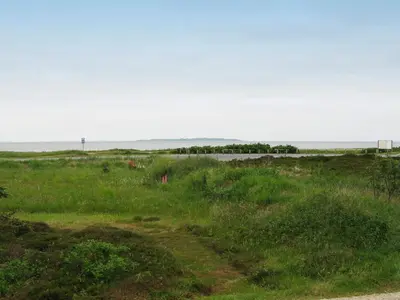 a dirt road in a field with the ocean in the background at 7 person holiday home in Løgstør-By Traum in Løgstør