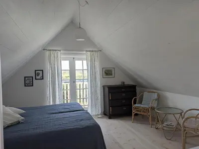 a bedroom with a blue bed and a window at Strandhuset in Agger
