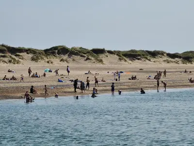a group of people on a beach with the water at Strandhuset in Agger