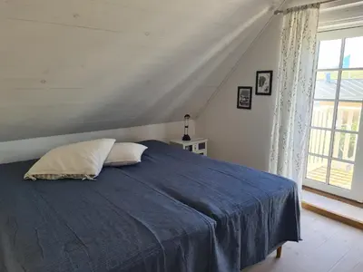 a bedroom with a blue bed and a window at Strandhuset in Agger