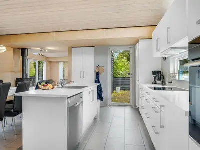 a kitchen with white cabinets and a dining room at Holiday Home Ginne - 1km to the fjord by Interhome in Løgstør