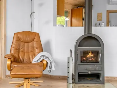 a leather chair in a living room with a stove at Holiday Home Selvi - 2-2km from the sea by Interhome in Blokhus
