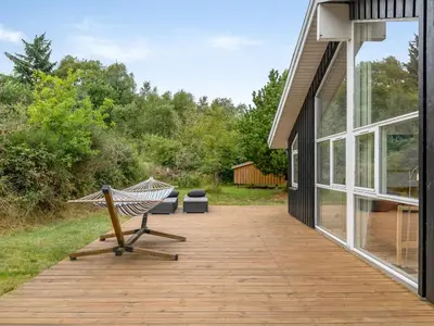 a hammock on a deck next to a house at Holiday Home Selvi - 2-2km from the sea by Interhome in Blokhus