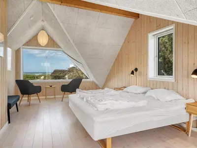 a bedroom with a bed and a table and chairs at Holiday Home Tekla - 180m from the sea by Interhome in Blokhus