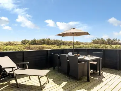 a patio with a table and an umbrella at Holiday Home Tekla - 180m from the sea by Interhome in Blokhus