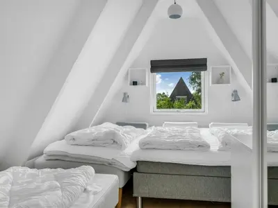 two beds in a attic room with a window at Holiday Home Ernstine by Interhome in Farsø