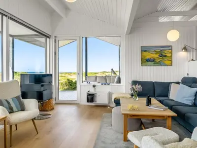 a living room with blue furniture and large windows at Holiday Home Jannus - 600m from the sea by Interhome in Saltum