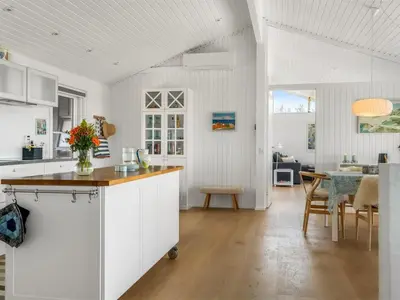 a kitchen with white cabinets and a dining room at Holiday Home Jannus - 600m from the sea by Interhome in Saltum