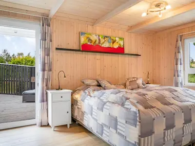a bedroom with a bed and a balcony at Holiday Home Eeske - 2-5km from the sea by Interhome in Blokhus