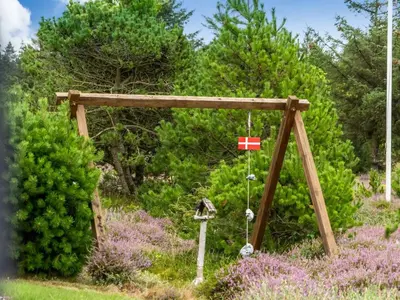 a wooden swing set in a field of flowers at Holiday Home Eeske - 2-5km from the sea by Interhome in Blokhus