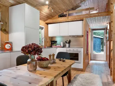 a kitchen with white cabinets and a wooden table at Holiday Home Melisa - 3km from the sea by Interhome in Pandrup
