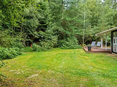 a yard with a porch and a deck with chairs at Holiday Home Melisa - 3km from the sea by Interhome in Pandrup