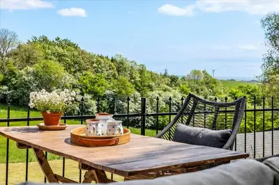 a wooden table sitting on top of a fence at Summer House Close To Nature By The Limfjord in Nykøbing Mors
