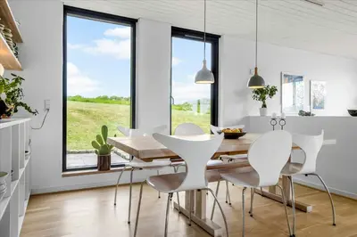 a dining room with a wooden table and white chairs at Summer House Close To Nature By The Limfjord in Nykøbing Mors