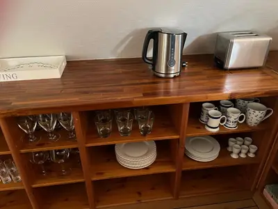 a wooden shelf with cups and glasses and a coffee maker at Stor lejlighed i landlige omgivelser in Bækmarksbro