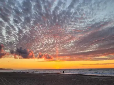 a person standing on the beach at sunset at 6 person holiday home in Brovst-By Traum in Brovst