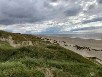 a beach with people walking on the sand at 6 person holiday home in Løkken-By Traum in Løkken