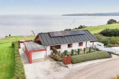 a house with solar panels on top of it next to the water at G295-Lemvig-Syrenvej-95 in Lemvig