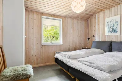 a bedroom with a bed in a wooden wall at LK1123-Lokken-Piasvej-16 in Løkken