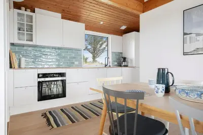 a kitchen with white cabinets and a table and a stove at LK2113-Lokken-Kettrup-Bjerge-vej-67 in Løkken