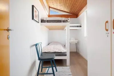 a small room with bunk beds and a chair at LK2113-Lokken-Kettrup-Bjerge-vej-67 in Løkken