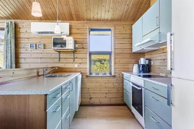 a kitchen with wooden walls and counters and a refrigerator at LK316-Lokken-Sarasvej-22 in Løkken