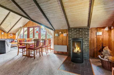 a living room with a fireplace and a table and chairs at LK473-Lokken-Kettrup-Bjerge-Vej-47 in Løkken