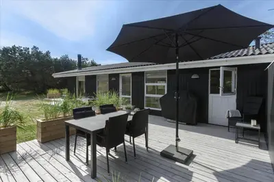 a table and chairs with an umbrella on a deck at LK1706-Lokken-Redningsstien-20-A in Løkken