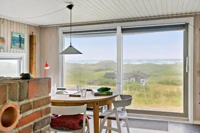 a dining room with a table and a large window at LK1456-Lokken-Magdavej-9 in Løkken