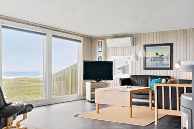 a living room with a television and large windows at LK1456-Lokken-Magdavej-9 in Løkken