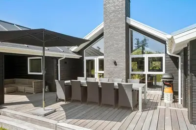 a patio with a table and chairs and an umbrella at LK1924-Lokken-Lydiavej-4 in Løkken