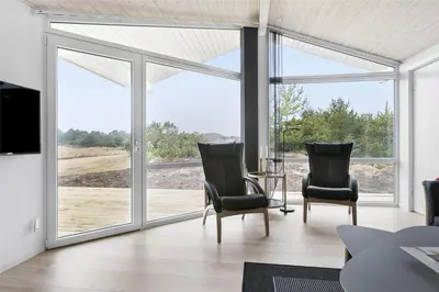 a living room with two chairs and sliding glass doors at LK1423-Lokken-Rikkesvej-4 in Løkken