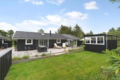 a backyard with a black house and a lawn at LK2087-Lokken-Karinavej-54 in Løkken