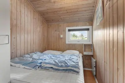 a bedroom with a bed in a wooden wall at LK1892-Lokken-Marthinesvej-37 in Løkken