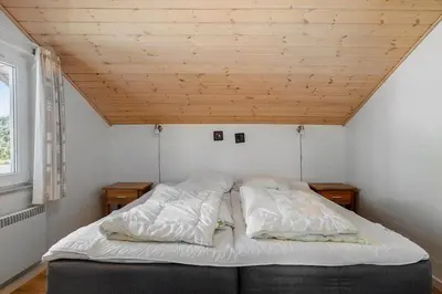 a bed in a room with a wooden ceiling at LK781-Lokken-Margrethevej-6 in Løkken