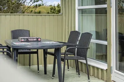 a table and chairs on a porch with a box on it at LK539-Lokken-Sylviavej-27 in Løkken